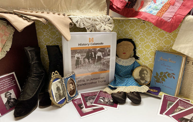 AFrican American Grandmothers educational trun including black button shoes, binder with teaching materials, a stuffed doll and a book