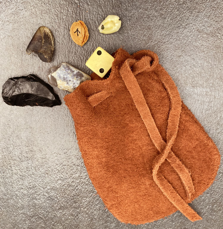 Leather pouch containing dice, shells, and rocks for games.